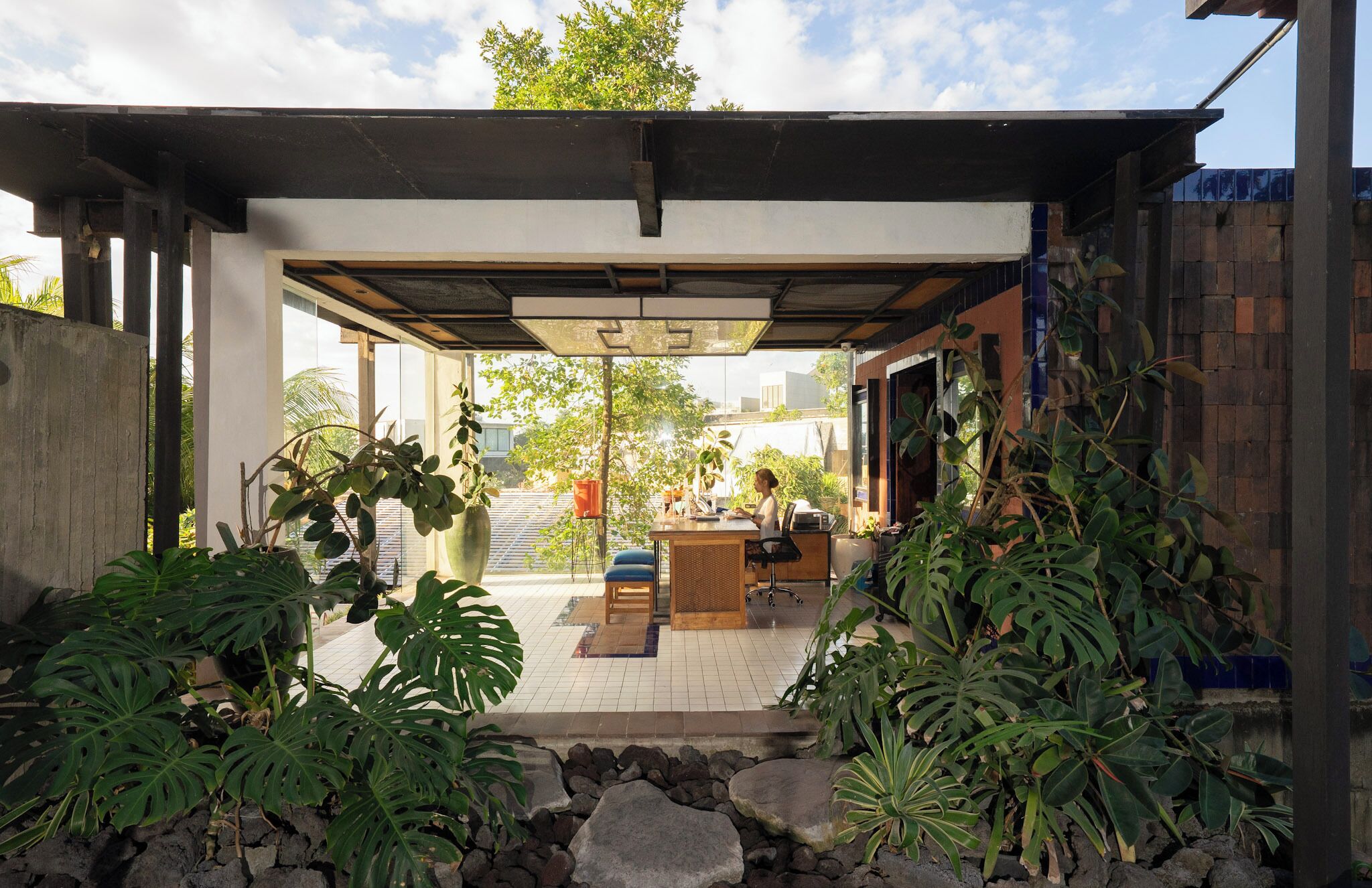 A covered outdoor area with a seating arrangement, a counter, and various plants.
