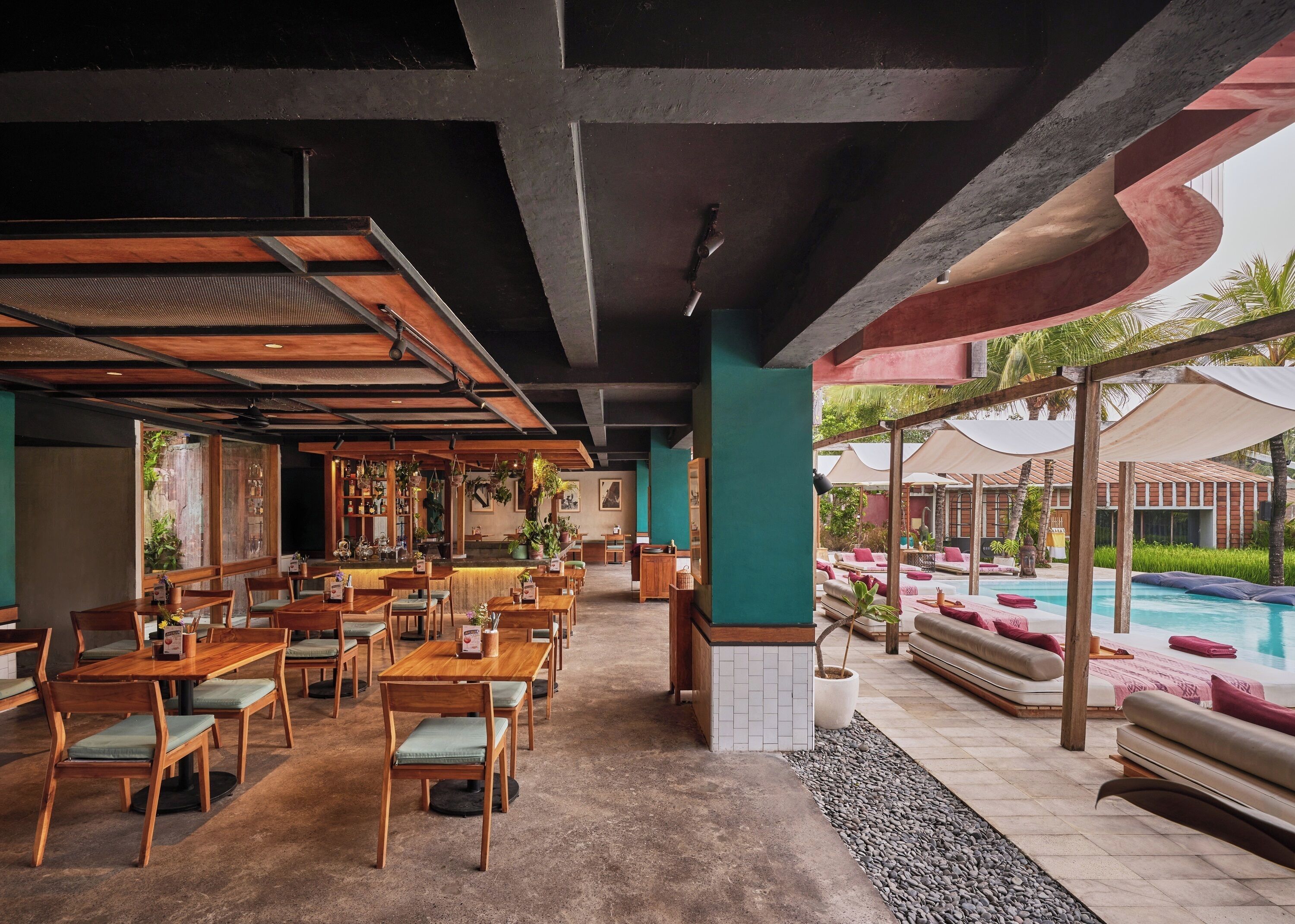 A restaurant with wooden tables and chairs, a bar area, and a poolside lounge with sun loungers.