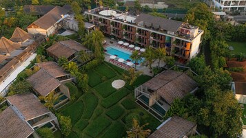 Oversigtsbillede af et resort med swimmingpool, flere bygninger og velholdte haver.