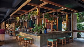 Un área de bar con vigas de madera, plantas colgantes y taburetes.