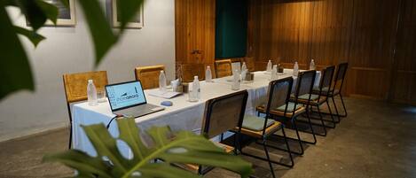 Ein Konferenzraum mit einem langen Tisch, Stühlen, einem Laptop und Wasserflaschen.