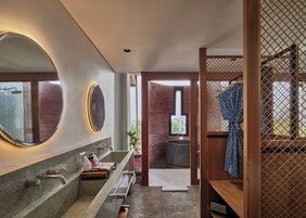 A modern bathroom with a large mirror, two sinks, a shower area, and a wooden partition.