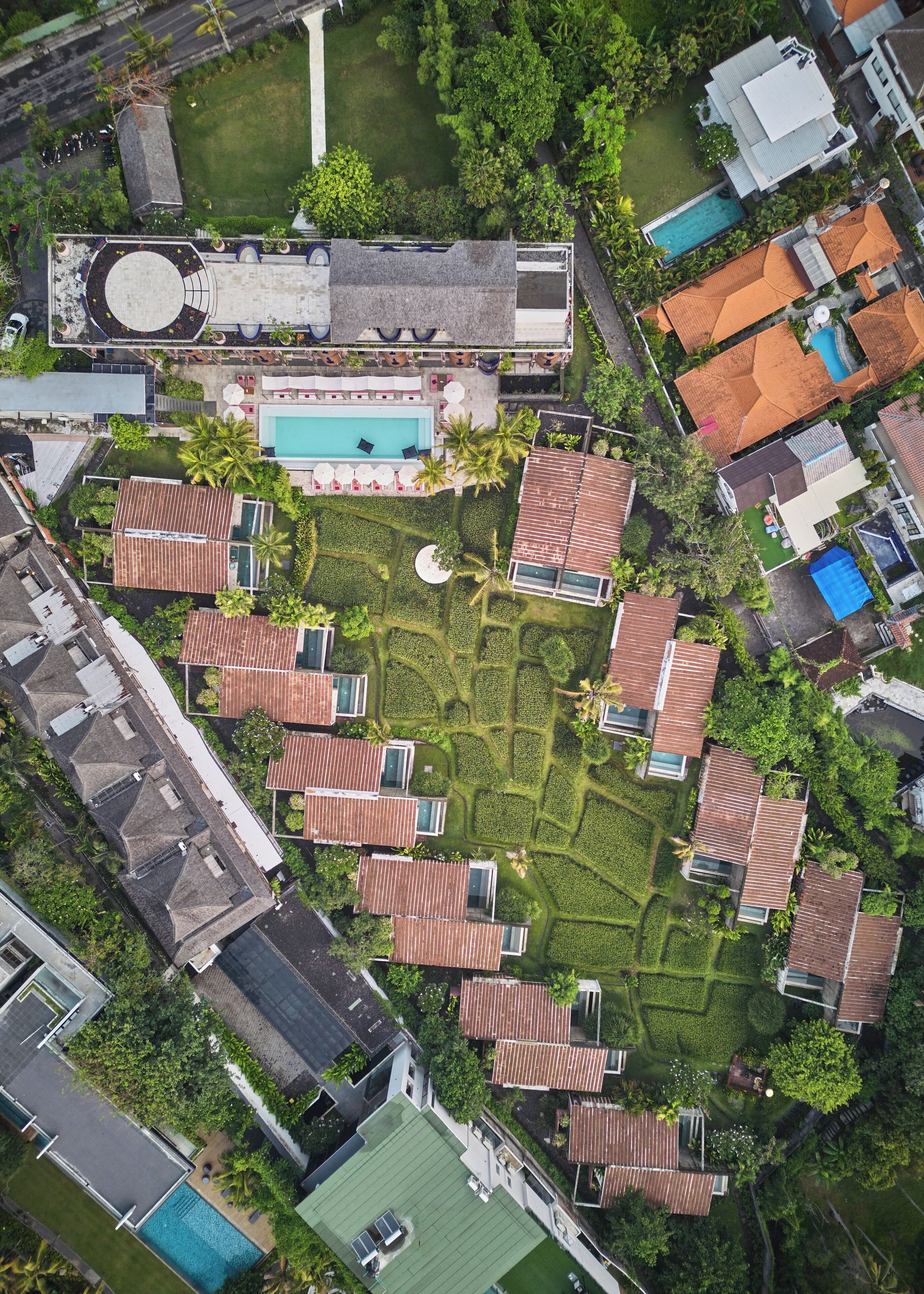 An aerial view of a residential area with multiple houses, a swimming pool, and well-maintained gardens.