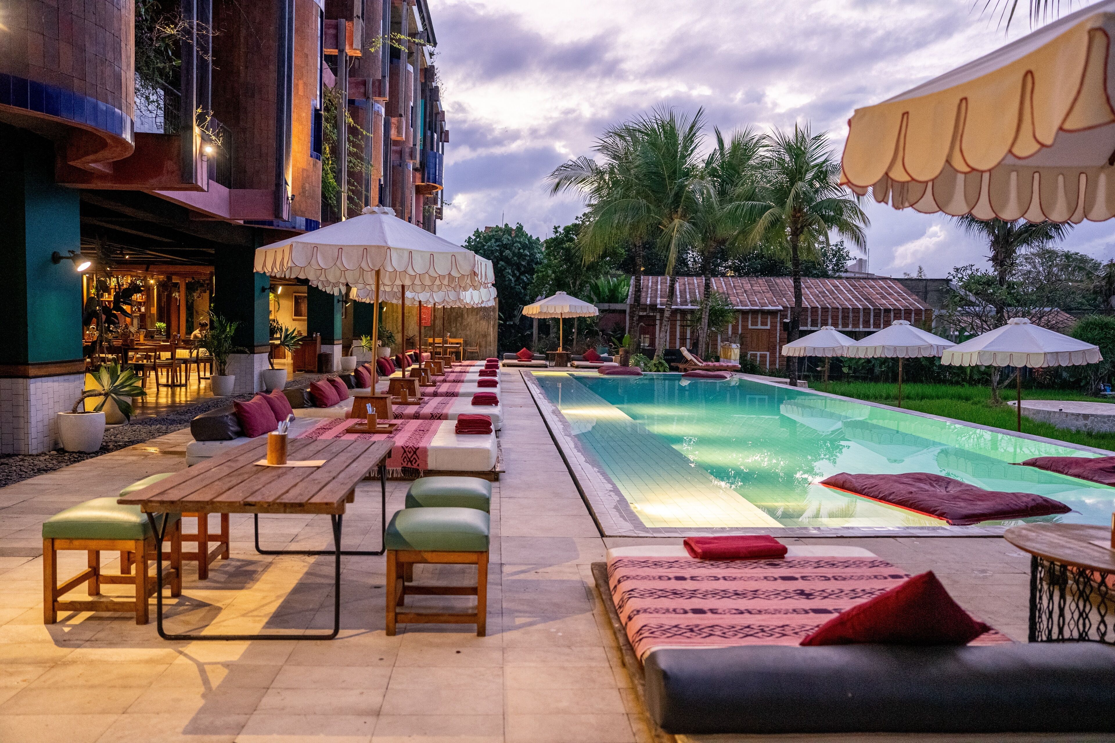 Zona de piscina con sillones, sombrillas y una pileta.