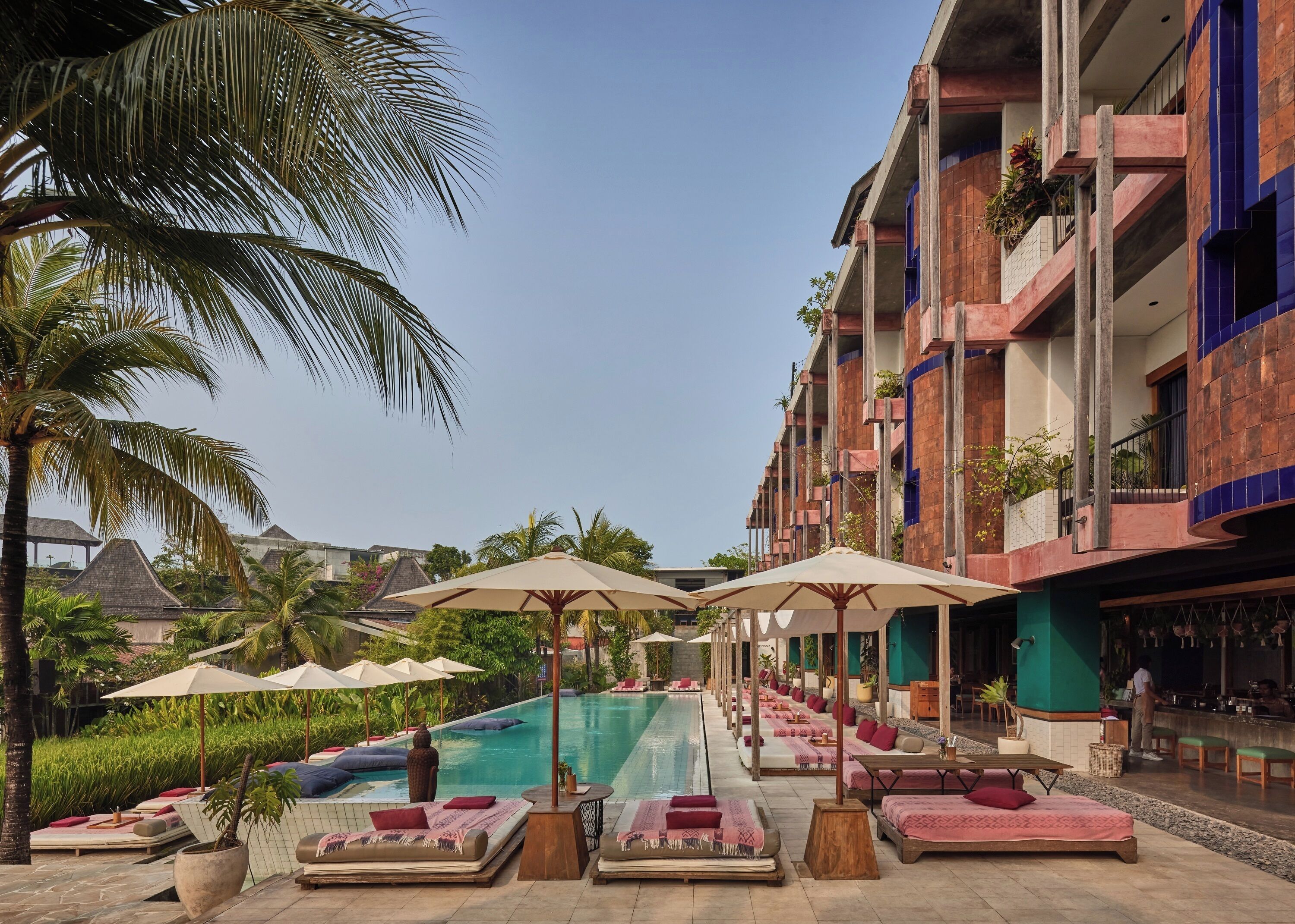 A poolside area with lounge chairs and umbrellas, a bar, and a building with balconies.