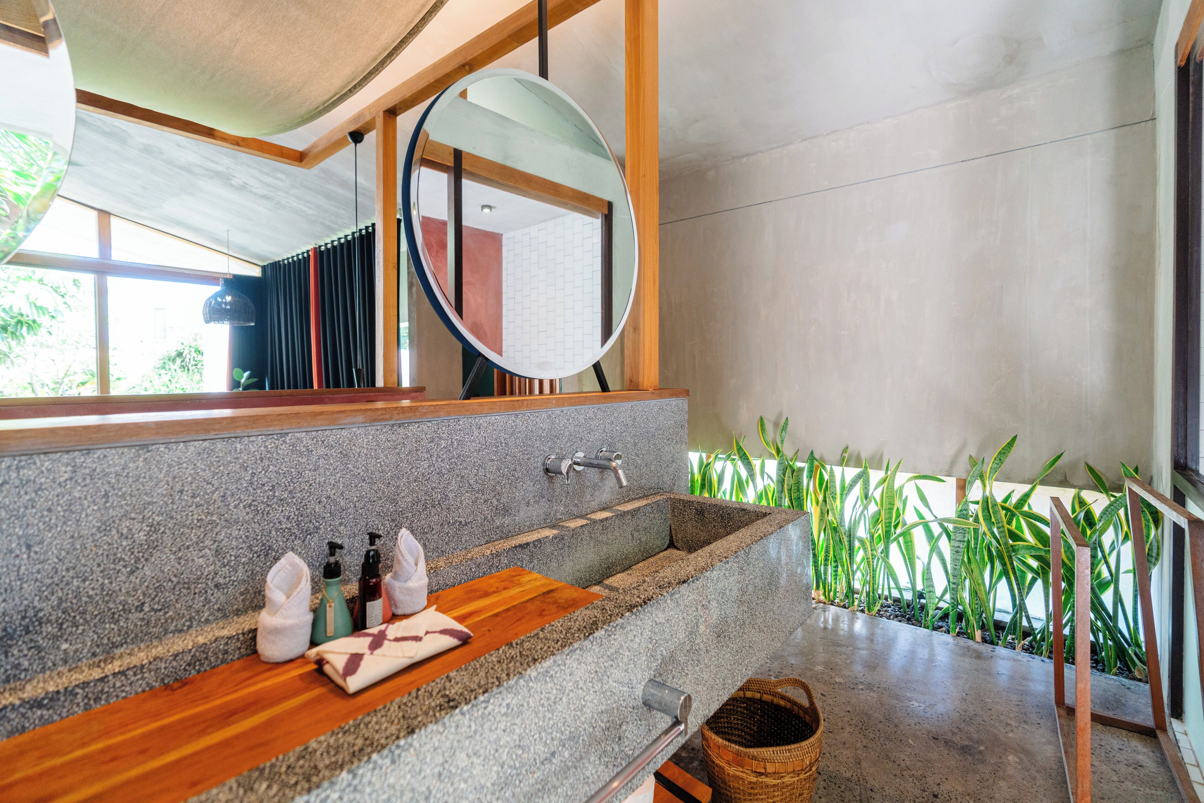 Une salle de bain avec un lavabo en pierre, un plan de toilette en bois et un miroir.