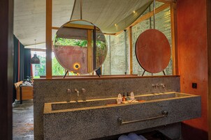 A bathroom with a granite sink, two mirrors, and a wooden bench.