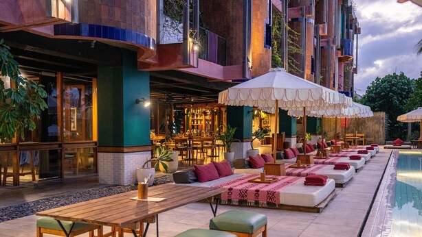 Un área de descanso junto a la piscina con asientos y un bar.