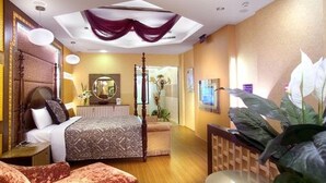 Habitación de hotel con una cama, mesita de noche y una planta grande en maceta.