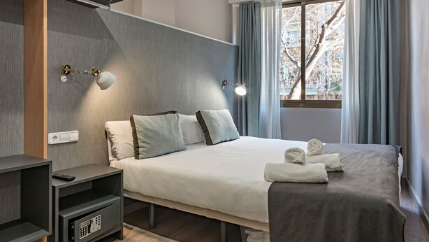 A modern hotel room with a bed, bedside tables, a TV stand, and a window with curtains. - Cool Jazz 24 - Habitat Apartments (Barcelona)