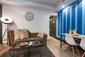 A modern living room with a sofa, coffee table, and a dining area with a table and chairs. - Cool Jazz 24 - Habitat Apartments (Barcelona)