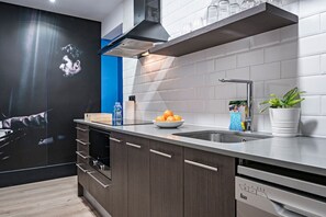 Een moderne keuken met een inbouwvaatwasser, een roestvrijstalen spoelbak en een zwarte afzuigkap.