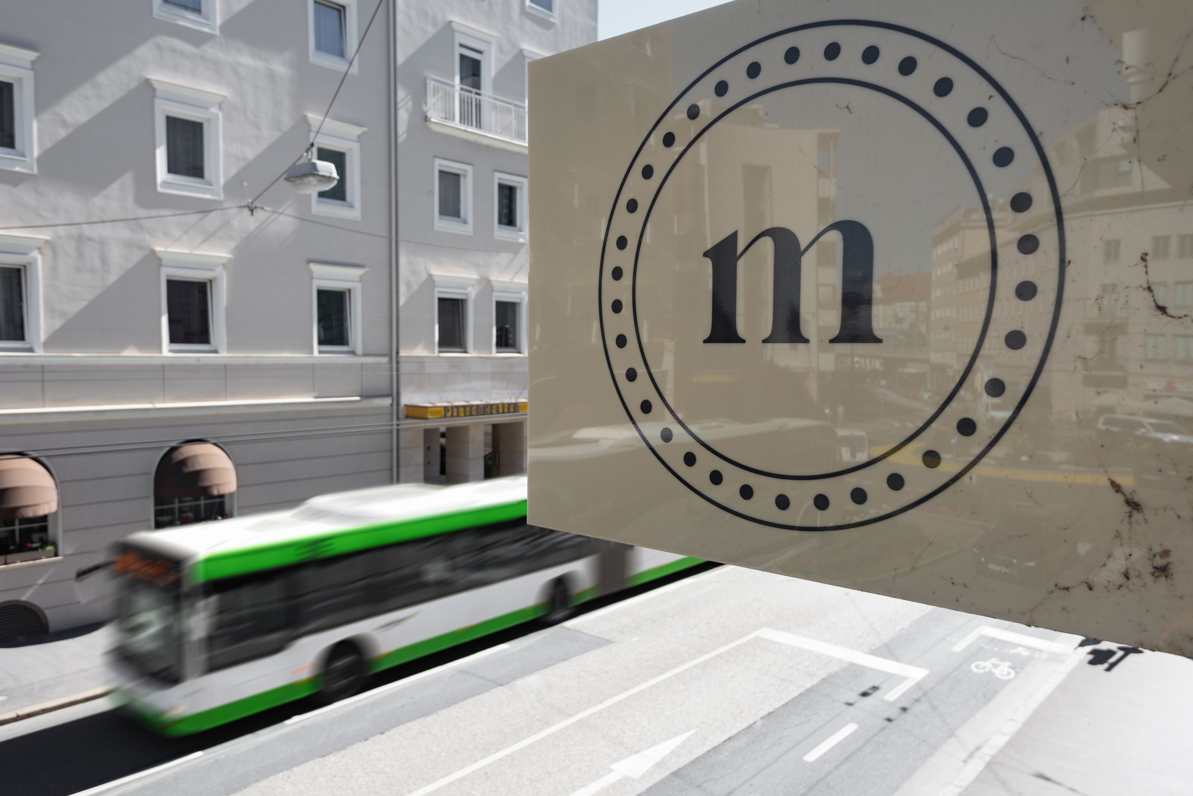 A building facade with a large circular logo featuring the letter 'm' and a tram in motion.