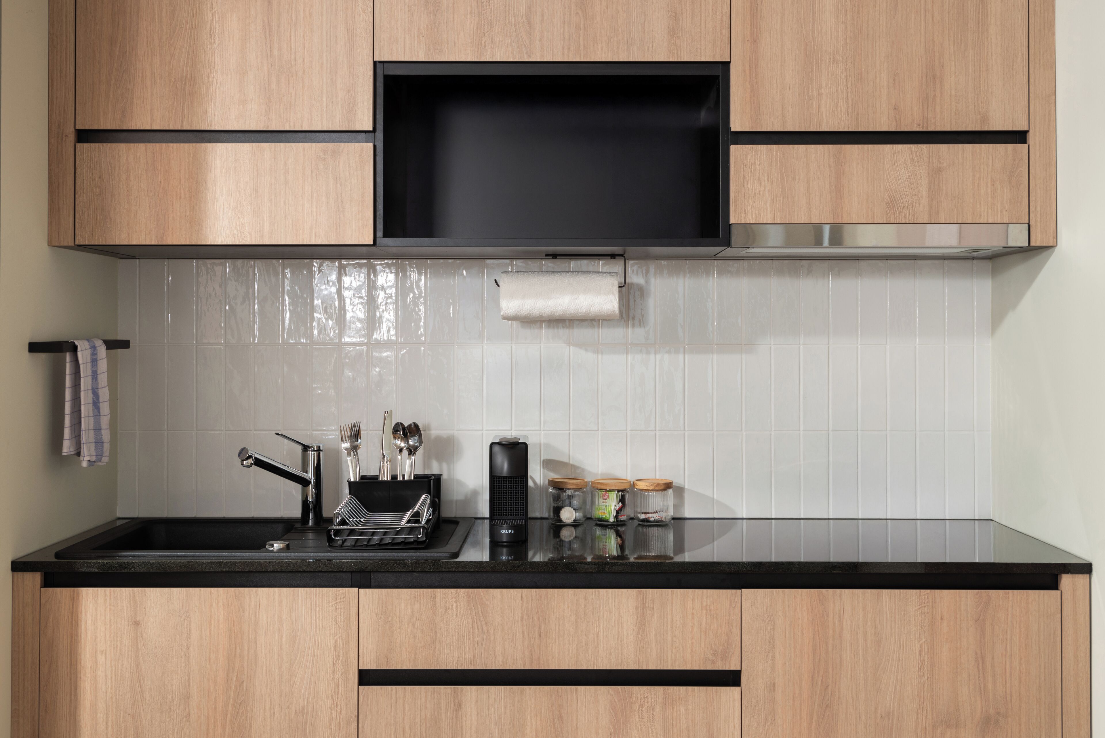 A modern kitchen with wooden cabinets, a black countertop, and a stainless steel range hood.