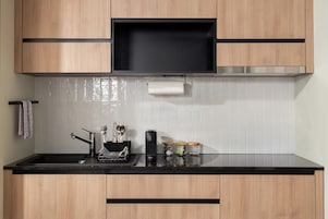 Una cocina moderna con armarios de madera, encimera negra y campana extractora de acero inoxidable.