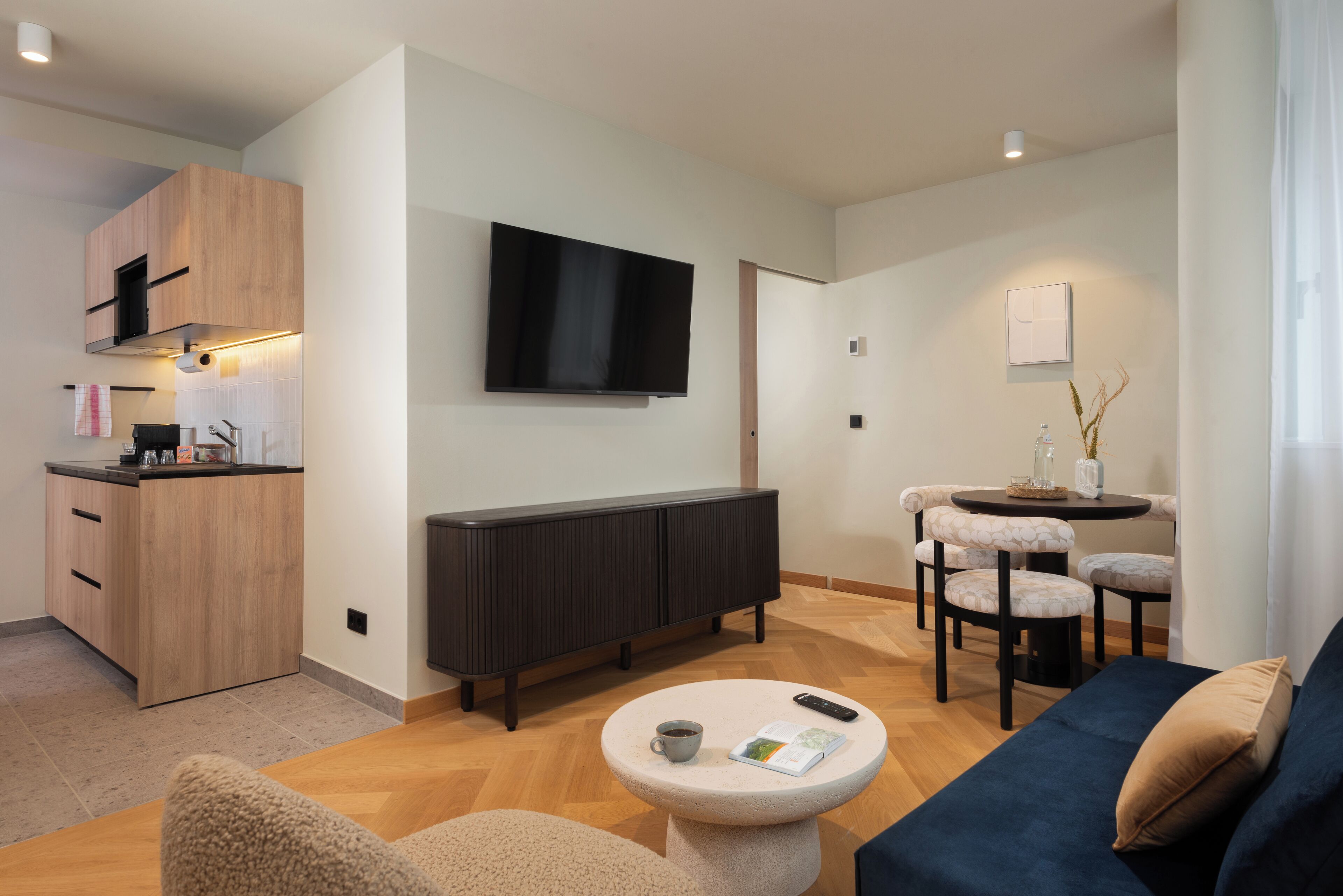Una sala de estar moderna con un sofá, una mesa de centro, un televisor y un comedor con sillas y una mesa.