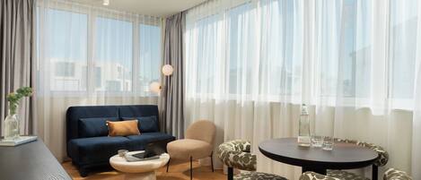 A modern living room with a sofa, armchairs, a round table, and a coffee table.