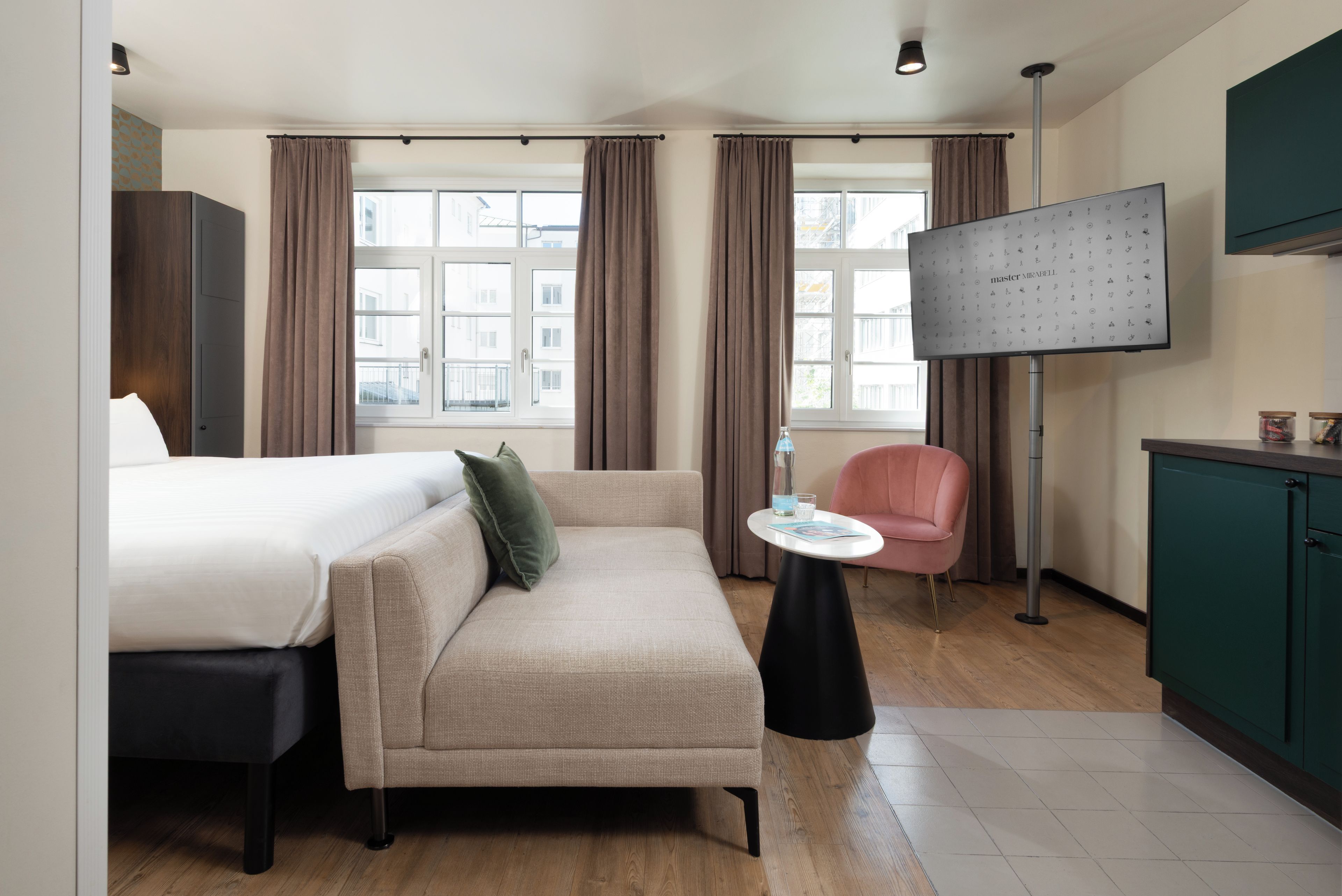 A hotel room with a bed, a sofa, a small table, a TV, and a cabinet.
