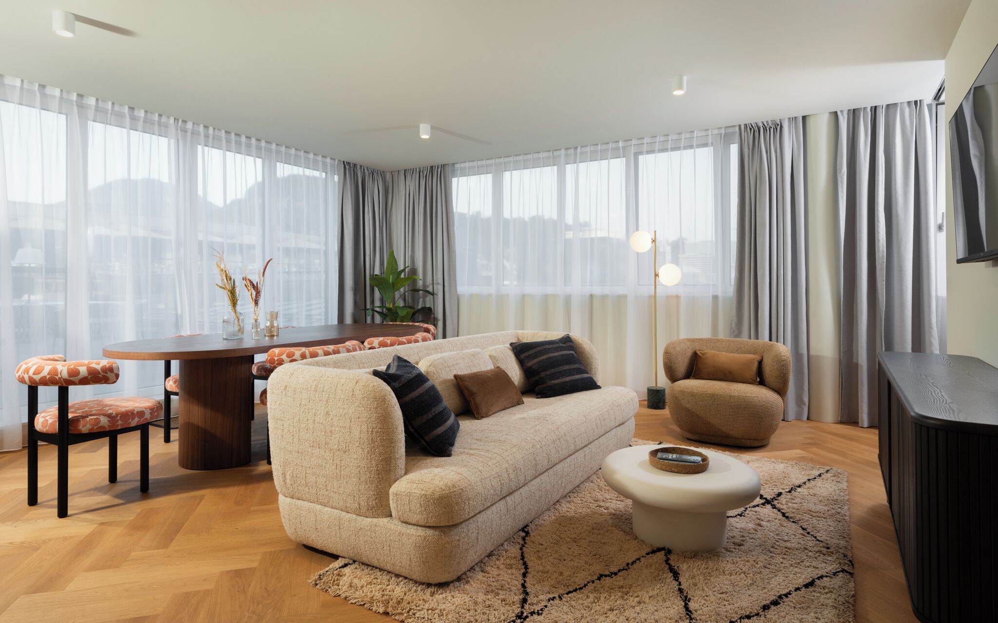 A modern living room with a sofa, coffee table, and a dining area.