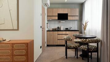 A modern kitchen with wooden cabinets, a black TV, and a dining area with four chairs.