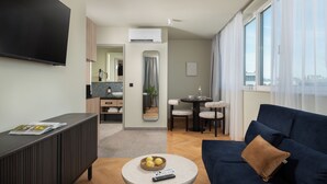 A modern living room with a dark blue sofa, a round coffee table with a remote control, and a magazine on a dark console table. - master Mirabell (Salzburg)