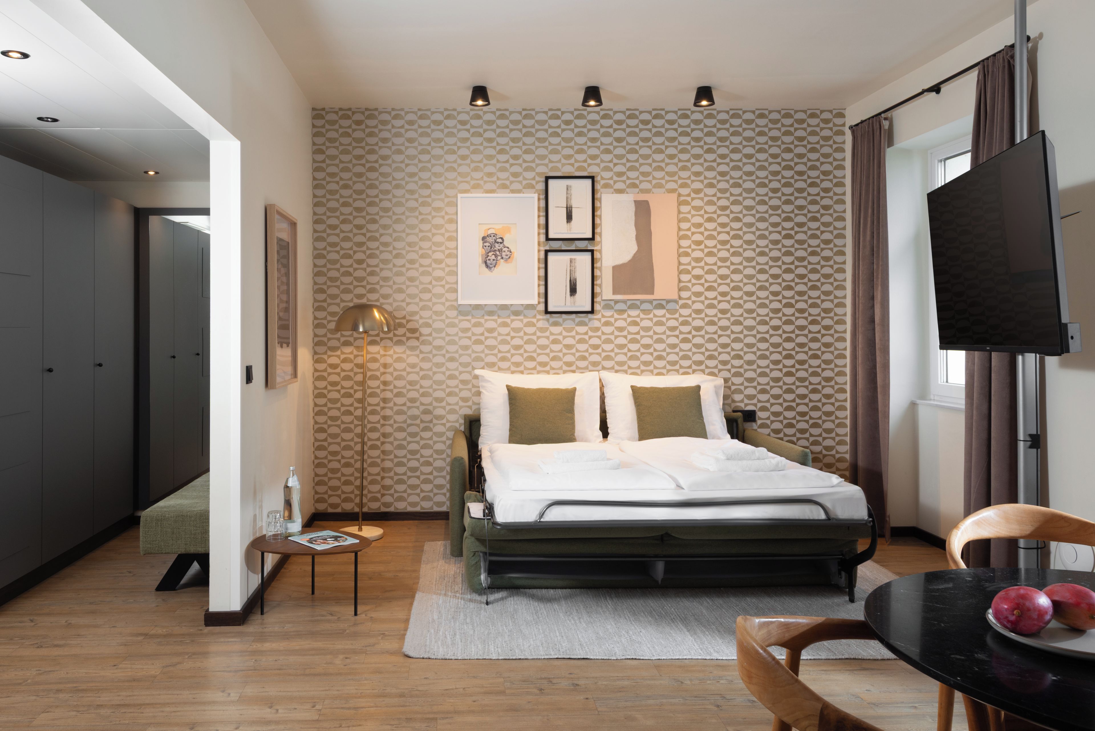 A modern bedroom with a bed, a TV, and artwork on the wall.