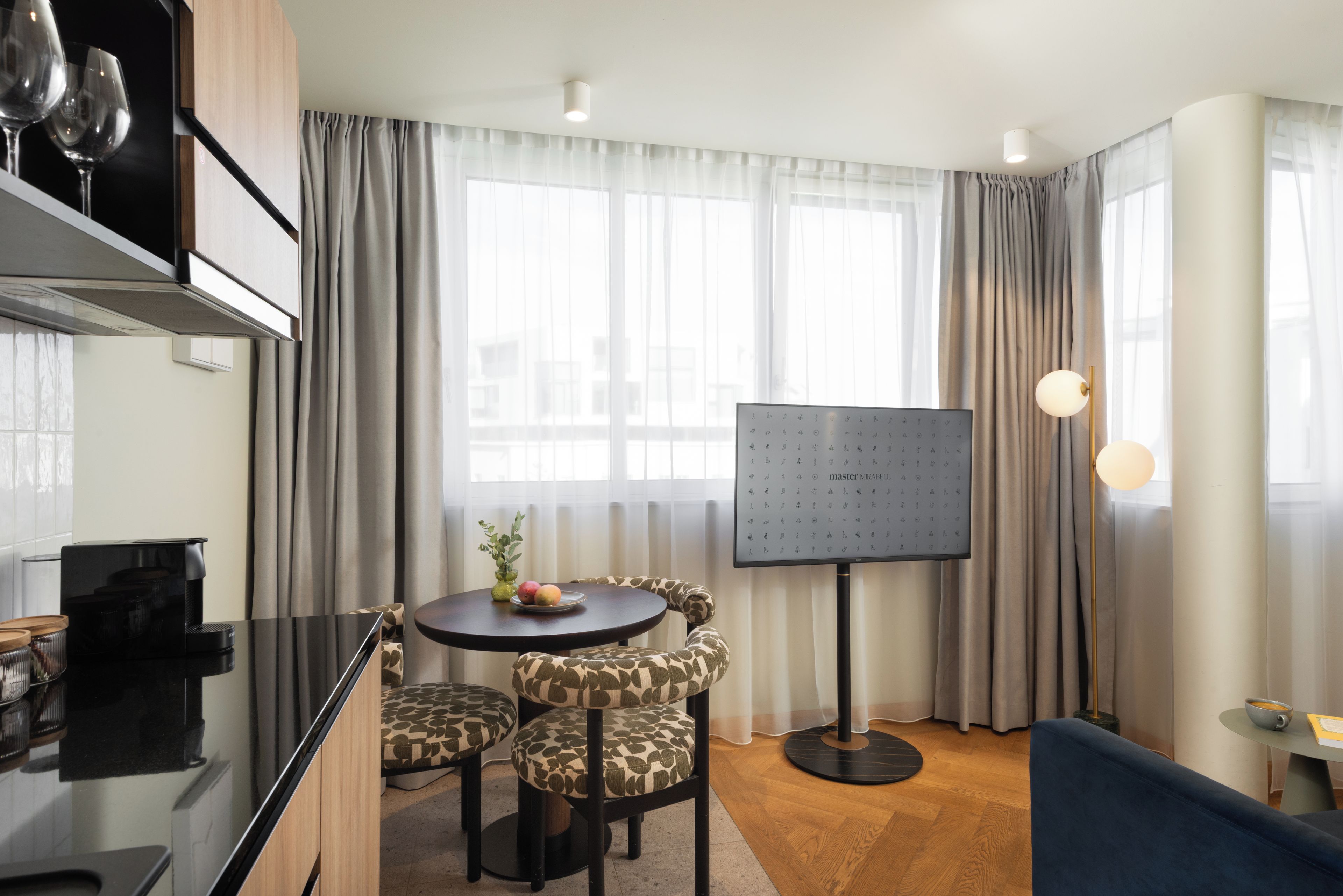 Un salon moderne avec une table ronde, des fauteuils à motifs, un téléviseur à écran plat et un canapé.
