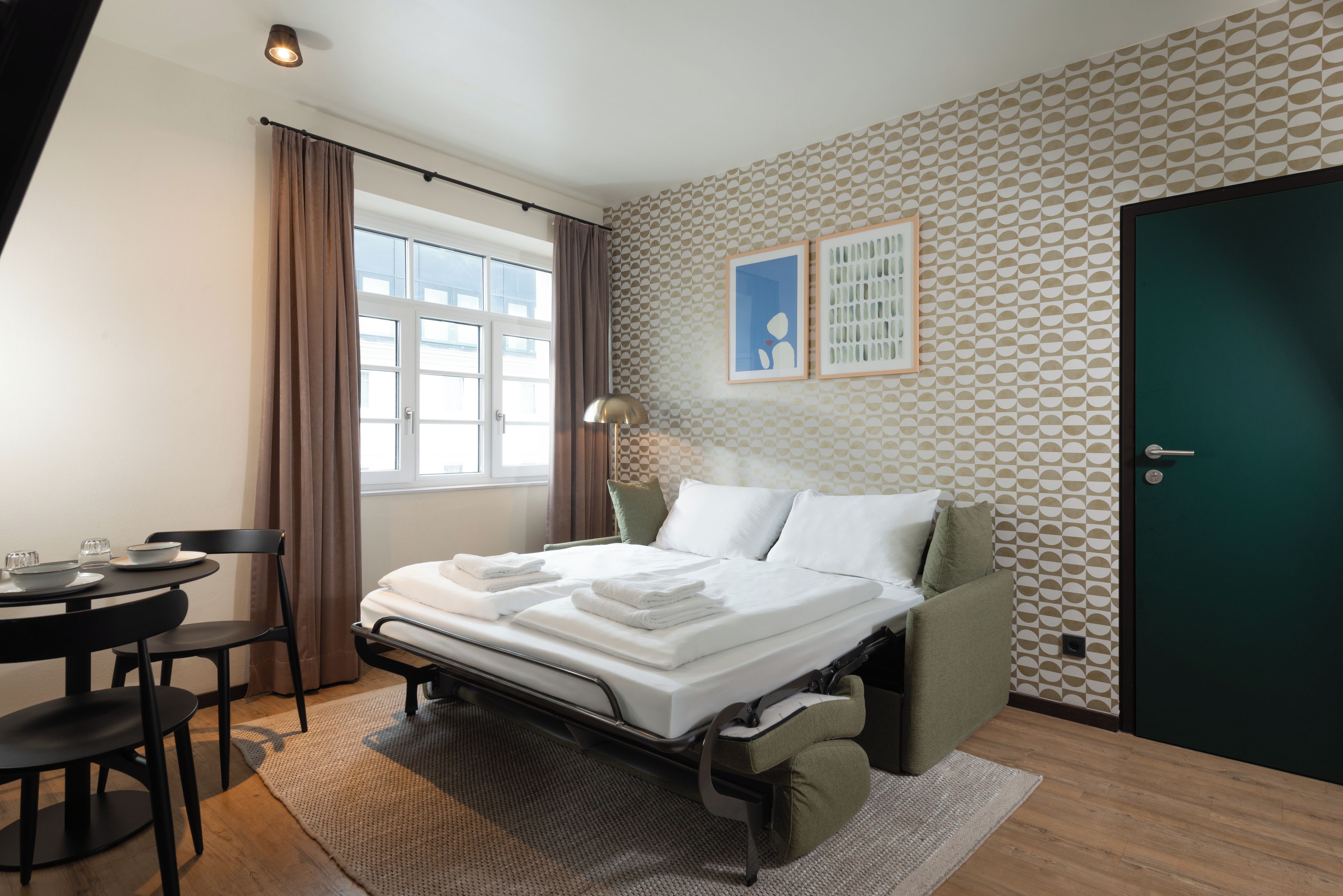 Una habitación de hotel con cama, escritorio, silla, ventana y puerta.