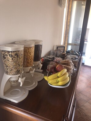 A buffet area with various food containers and a plate of bananas.