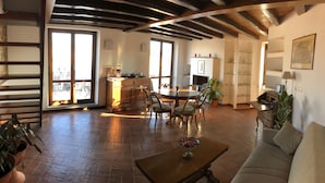 A spacious living room with a wooden floor, a dining area with a round table, and a kitchen in the background. - BB Il Re Alla Reginella Guest House (Rome)