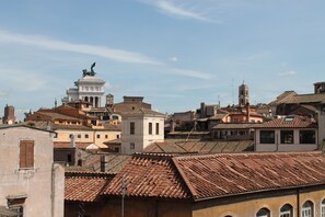 A historic town with terracotta-tiled roofs, a prominent statue on a pedestal, and a mix of traditional and modern architecture.
