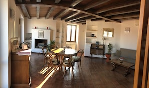 Un comedor amplio con una mesa y sillas de madera, una chimenea y vistas al exterior a través de un ventanal.