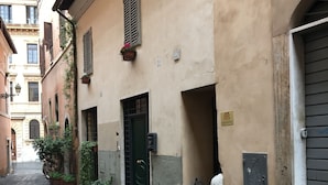A narrow cobblestone street with buildings on either side. There are potted plants and a green door visible. - BB Il Re Alla Reginella Guest House (Rome)