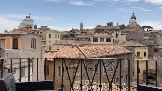 A terrace with wicker furniture and a view of a historic town with buildings and a tower. - BB Il Re Alla Reginella Guest House (Rome)