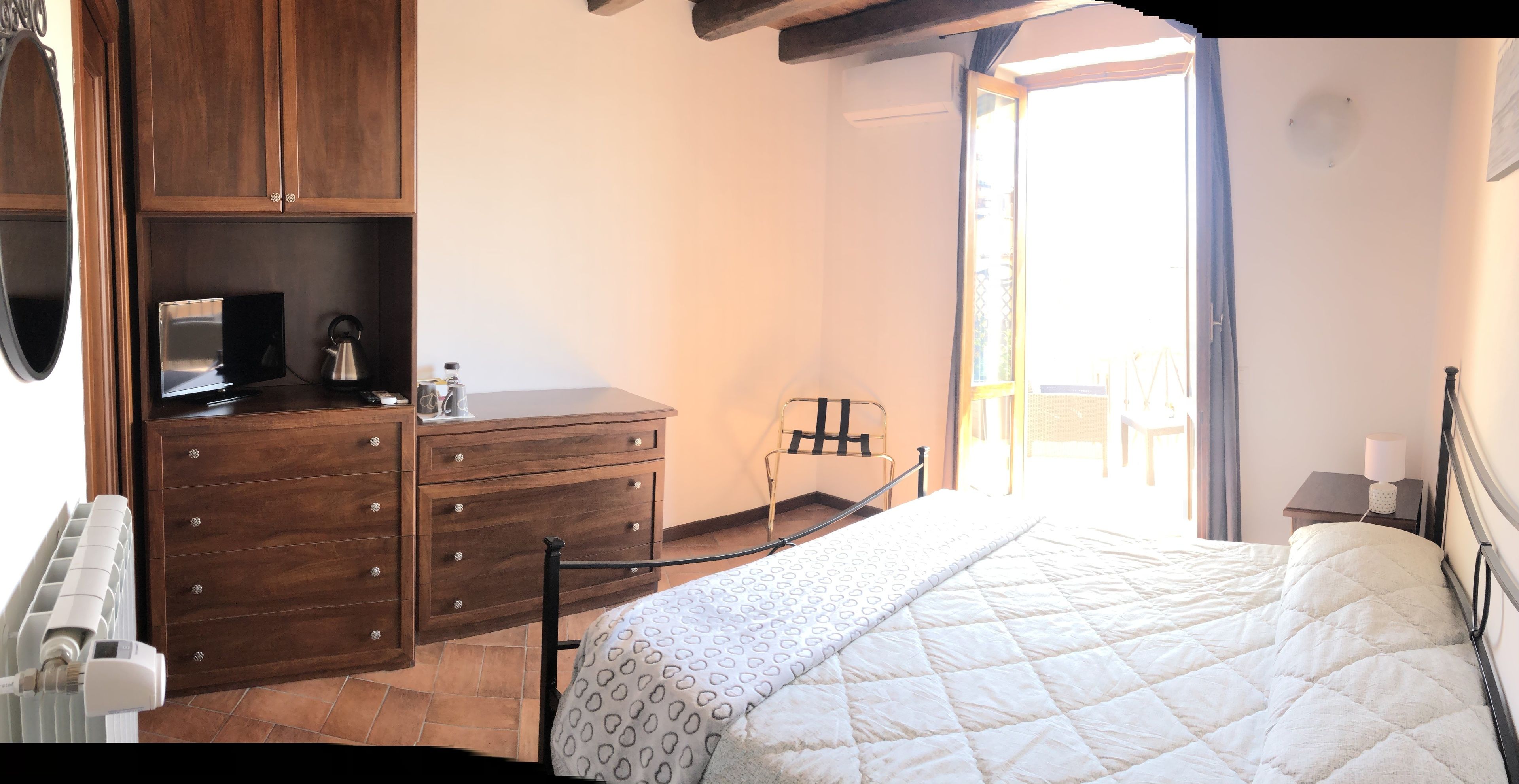 A bedroom with a bed, wooden dresser, and a radiator.