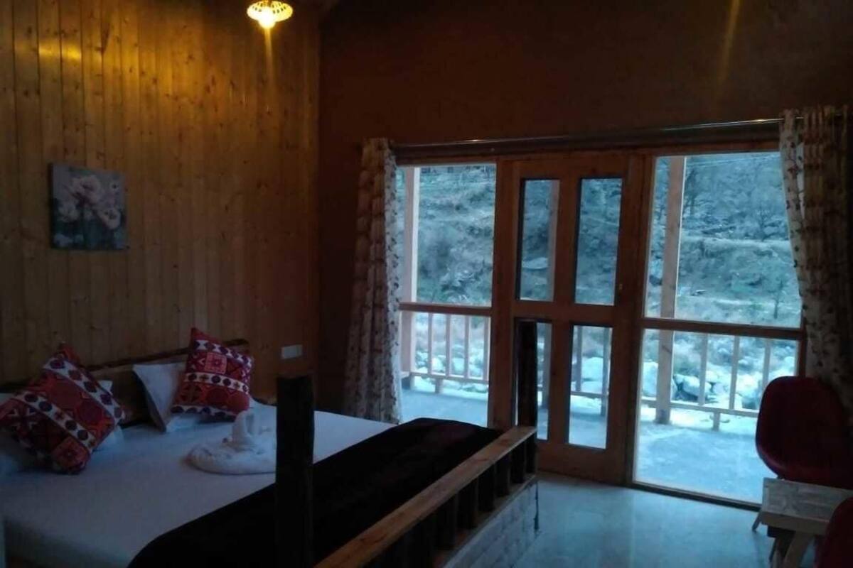 A wooden room with a bed, a window, and a view of a snowy landscape.