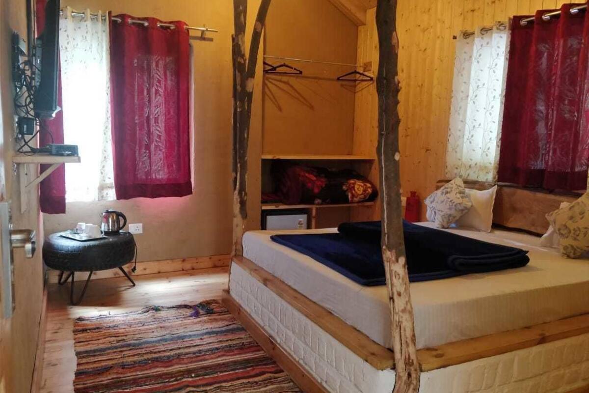 A cozy bedroom with a bed, a small table with a kettle, and a wardrobe.