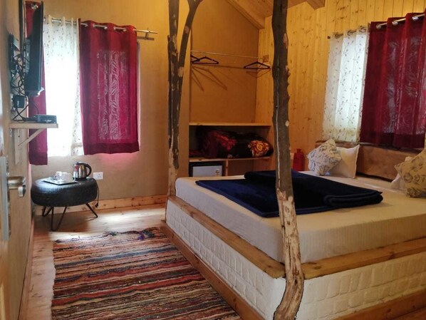Een gezellige slaapkamer met een bed, een klein tafeltje met waterkoker en een kledingkast.