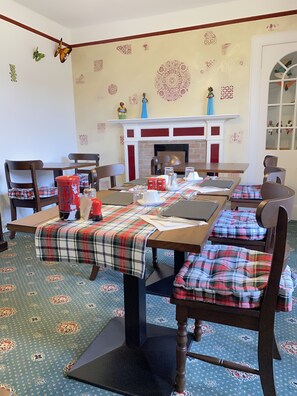 A dining area with a long table, plaid tablecloth, and chairs with plaid cushions. - Garden Park Guest House (Grantown-on-Spey)