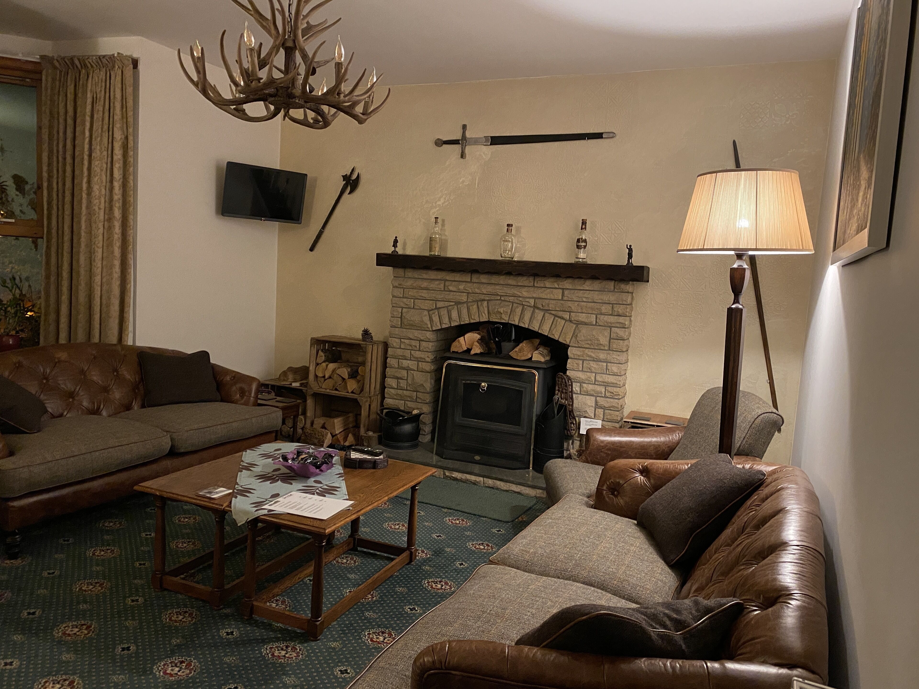 A cozy living room with a fireplace, leather sofas, a coffee table, and a television.