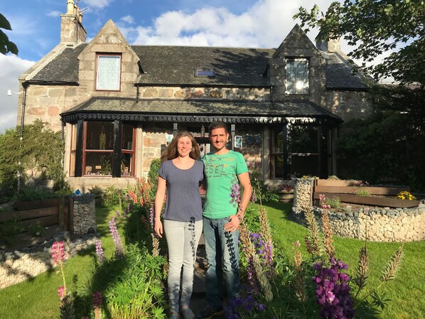 A stone house with a traditional design, featuring a prominent gabled roof and a small porch with a tiled roof. - Garden Park Guest House (Grantown-on-Spey)