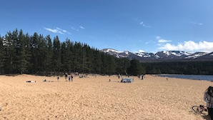 Una playa con zona boscosa y montañas al fondo.
