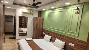 Un dormitorio con cama, cabecera de madera, paneles de pared verdes, ventilador de techo y lámpara colgante.