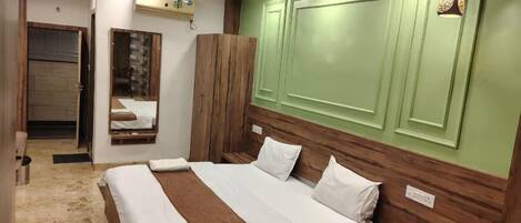 A bedroom with a bed, wooden headboard, green wall paneling, a ceiling fan, and a hanging light fixture.