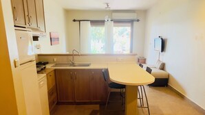 A compact kitchen with a dining area, a built-in oven, and a window with curtains. - Yelkovan Ada Evi (Marmara)
