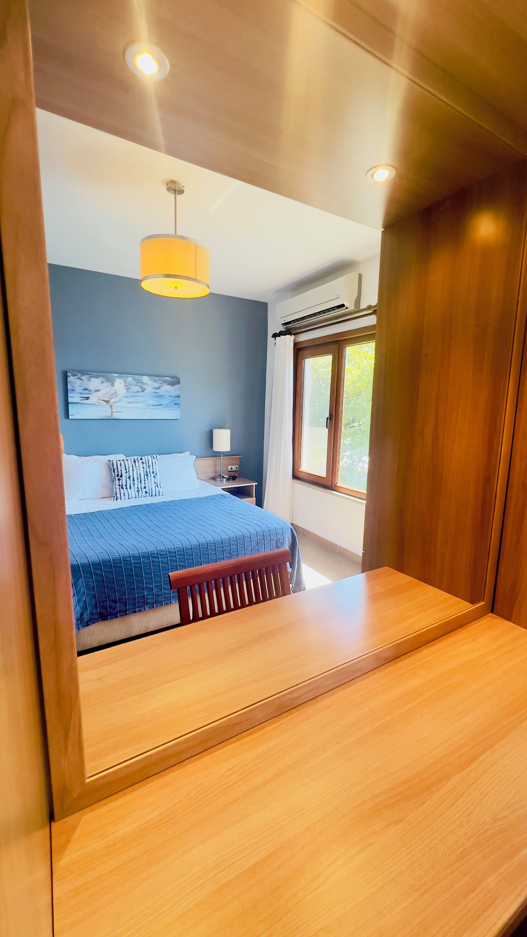 A bedroom with a bed, bedside table, lamp, and a window with curtains.