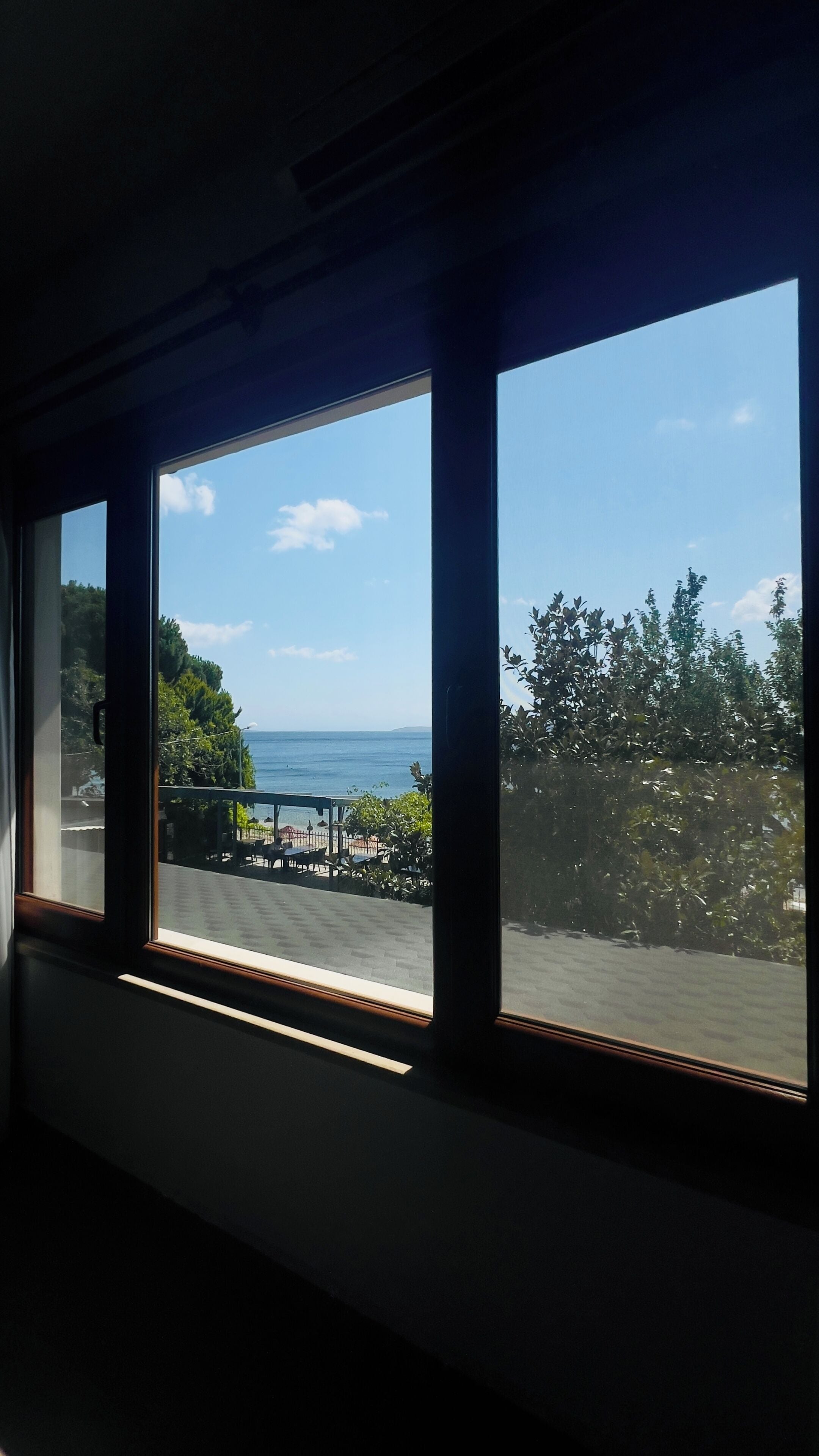 Ein Zimmer mit großen Fenstern und Blick auf eine Küstenlandschaft, inklusive Meer und einer fernen Insel.