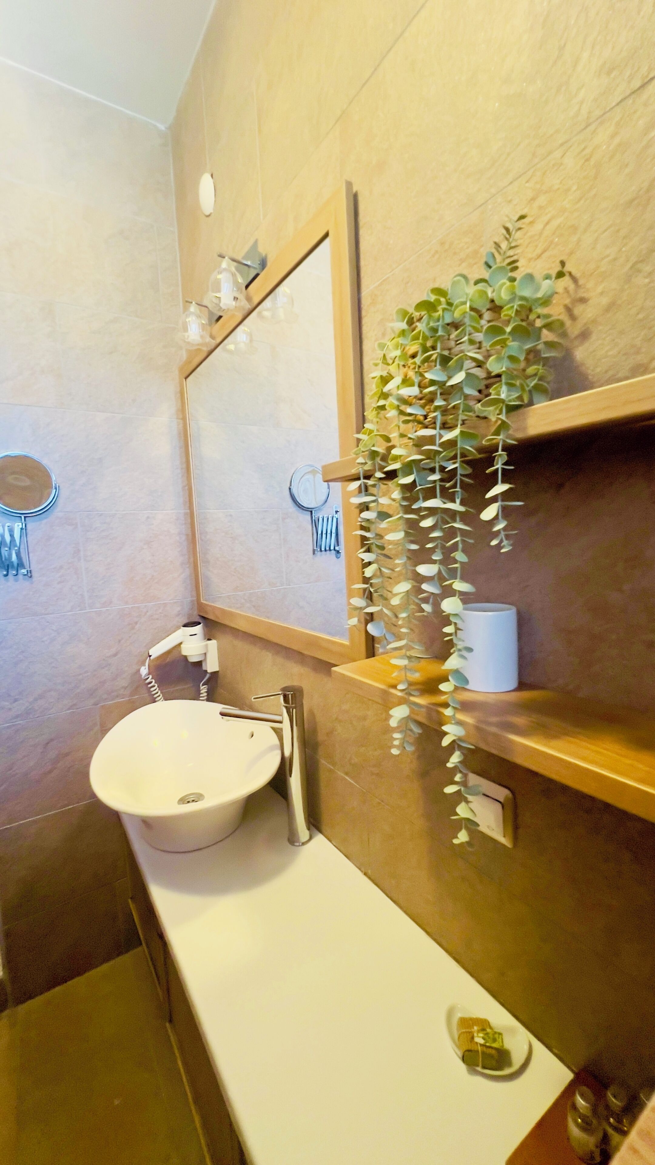Een badkamer met een wit wastafelmeubel, een spiegel en een hangplant.