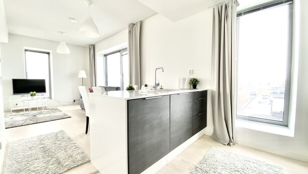 A modern apartment with a kitchen island, large windows, and a flat-screen TV. - City Center Tower Apartment (Tampere)