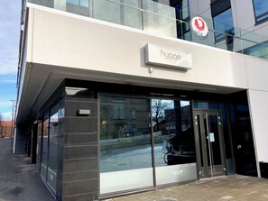 A modern building with a glass facade and a sign reading "hygge BISTRO-CAFE". - City Center Tower Apartment (Tampere)